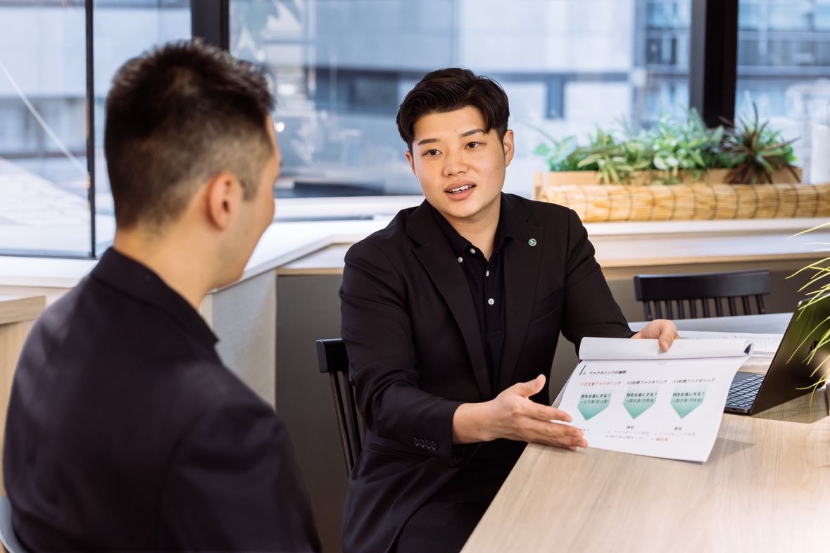 資料を用いて経営者と向き合う営業社員